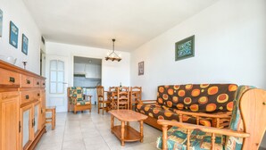 Ein Wohnzimmer mit einer Couch, Stühlen, einem Holzkabinett und einem Esstisch.
