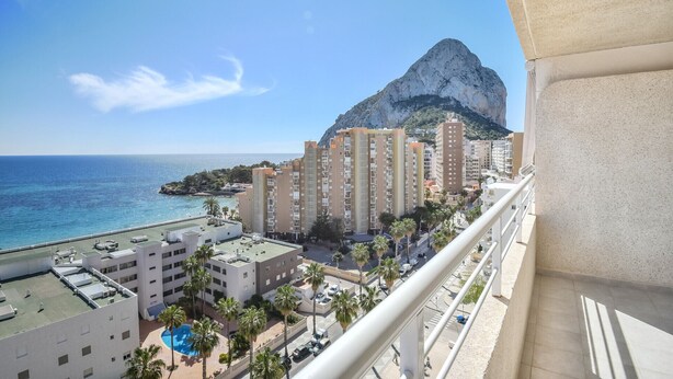 Ein Hochhotel mit Pool auf dem Dach, ein Berg im Hintergrund und Blick auf das Meer.