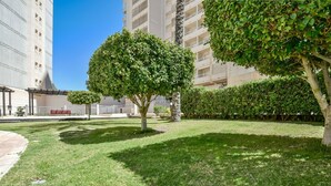 Une cour bien entretenue, avec une pelouse, quelques arbres et, au fond, un immeuble à plusieurs étages doté de balcons.
