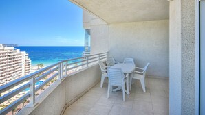 Varanda com mesa e cadeiras, vista para a praia e oceano.