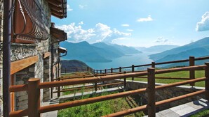 A stone building with a wooden balcony overlooking a lake and mountains. - Lovely apartment in villa for 6 guests with WIFI, TV and patio (Livo)