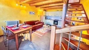 A cozy room with a wooden ceiling, a dining table set with plates and a bottle, a sofa, and a kitchen in the background. - Lovely apartment in villa for 6 guests with WIFI, TV and patio (Livo)