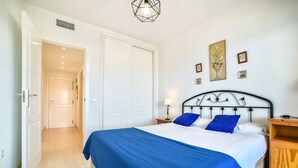 A bedroom with a bed, a nightstand, a lamp, and a wall with framed pictures. - Apolo XVII 1-14-41, La Fossa -Salinas (Calpe)