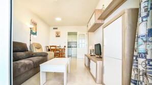 A living room with a sofa, a coffee table, and a TV on a wooden stand. - Apolo XVII 1-14-41, La Fossa -Salinas (Calpe)