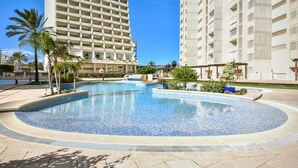 A swimming pool surrounded by palm trees and modern buildings. - Apolo XVII 1-14-41, La Fossa -Salinas (Calpe)