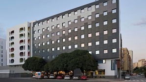 A modern hotel with a grid of windows, a sign reading 'Four Points Flex,' and a tree in front.