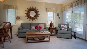 A living room with a sofa, armchair, coffee table, and a decorative mirror. - Teal Lake 2323 (North Myrtle Beach)