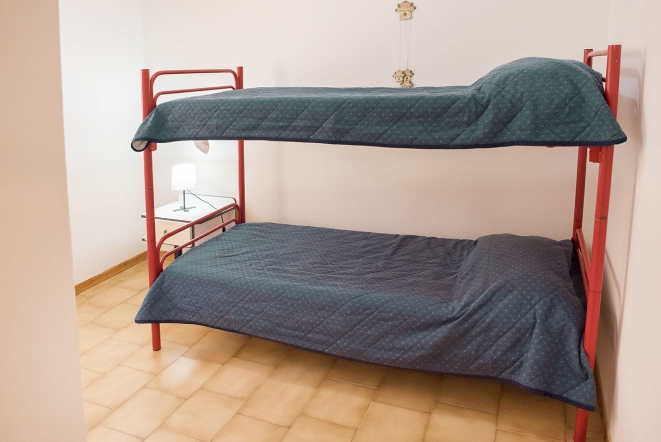 A bunk bed with a quilted mattress and a metal frame.