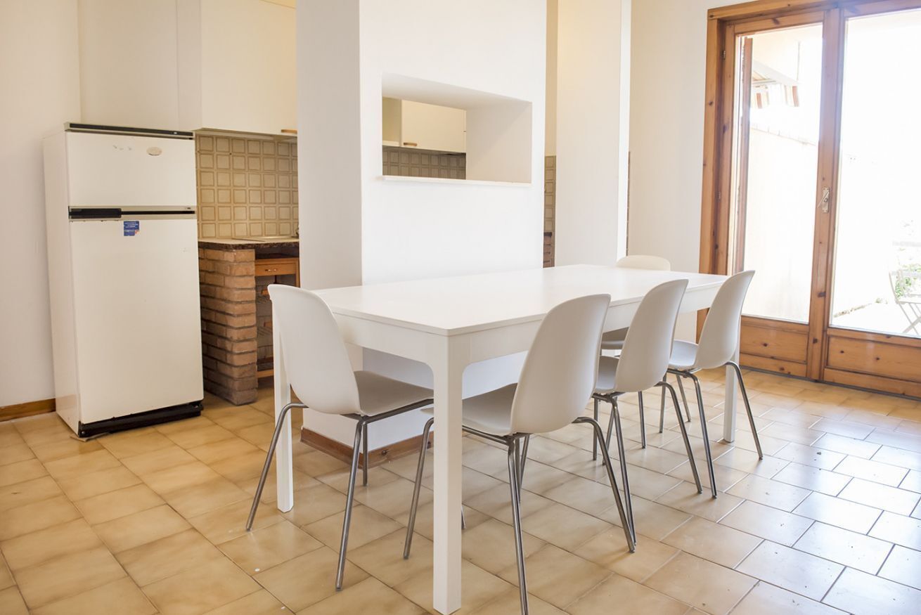 Una cucina con un tavolo e sedie bianchi, un frigorifero e un forno a mattoni.