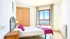 Une chambre à coucher avec un lit, une table de chevet en bois, une fenêtre donnant sur un paysage agréable et un radiateur.