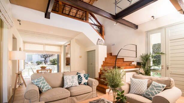 A spacious living room with a high ceiling, a wooden staircase, and a view of the outdoors. - Villa Lithia Ano Korakiana (Ano Korakiana)