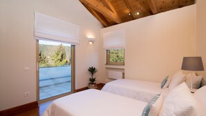 A bedroom with two beds, a potted plant, and a view of a balcony. - Villa Lithia Ano Korakiana (Ano Korakiana)