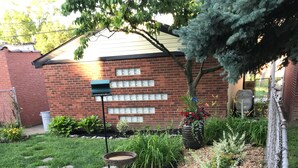 A garden with a bird bath, various plants, and a brick building in the background. - World’s Fair Charm -Two Story 3 bdrm (St. Louis)