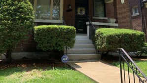 A two-story house with a front porch, a brick facade, and a black front door. - World’s Fair Charm -Two Story 3 bdrm (St. Louis)