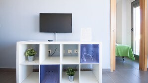 A room with a flat-screen TV mounted on a white console with multiple shelves, some holding potted plants.