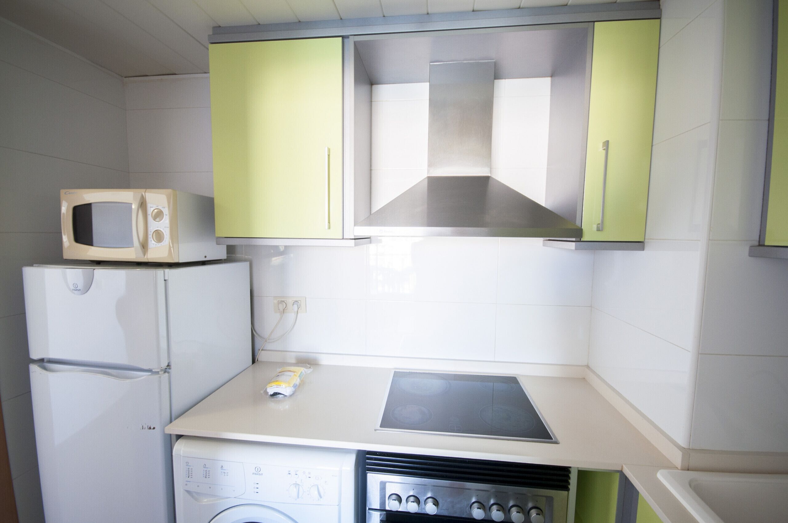 A compact kitchen with a microwave, stove, and washing machine.