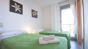 Two twin beds with green bedspreads, white pillows, and neatly folded towels.