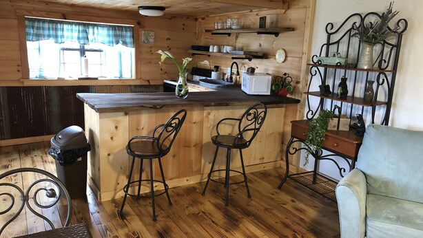 A cozy kitchen with wooden walls, a bar area with stools, and a dining table.