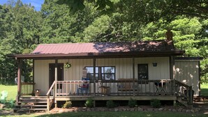 A rustic cabin with a porch, wooden deck, and a small garden area.