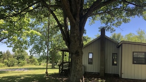 A single-story building with a porch, surrounded by trees and a grassy yard.