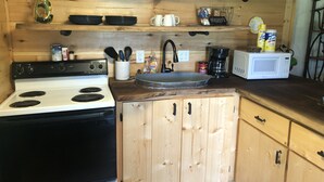 A kitchen with a white stove, wooden cabinets, a sink, and various kitchen items like cups, plates, and a coffee maker.