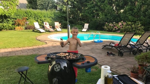 Un patio trasero con una parrilla, una piscina y sillas de descanso.