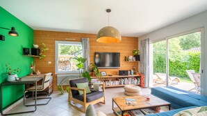 A modern living room with a TV, sofa, coffee table, and a dining area with a table and chairs.