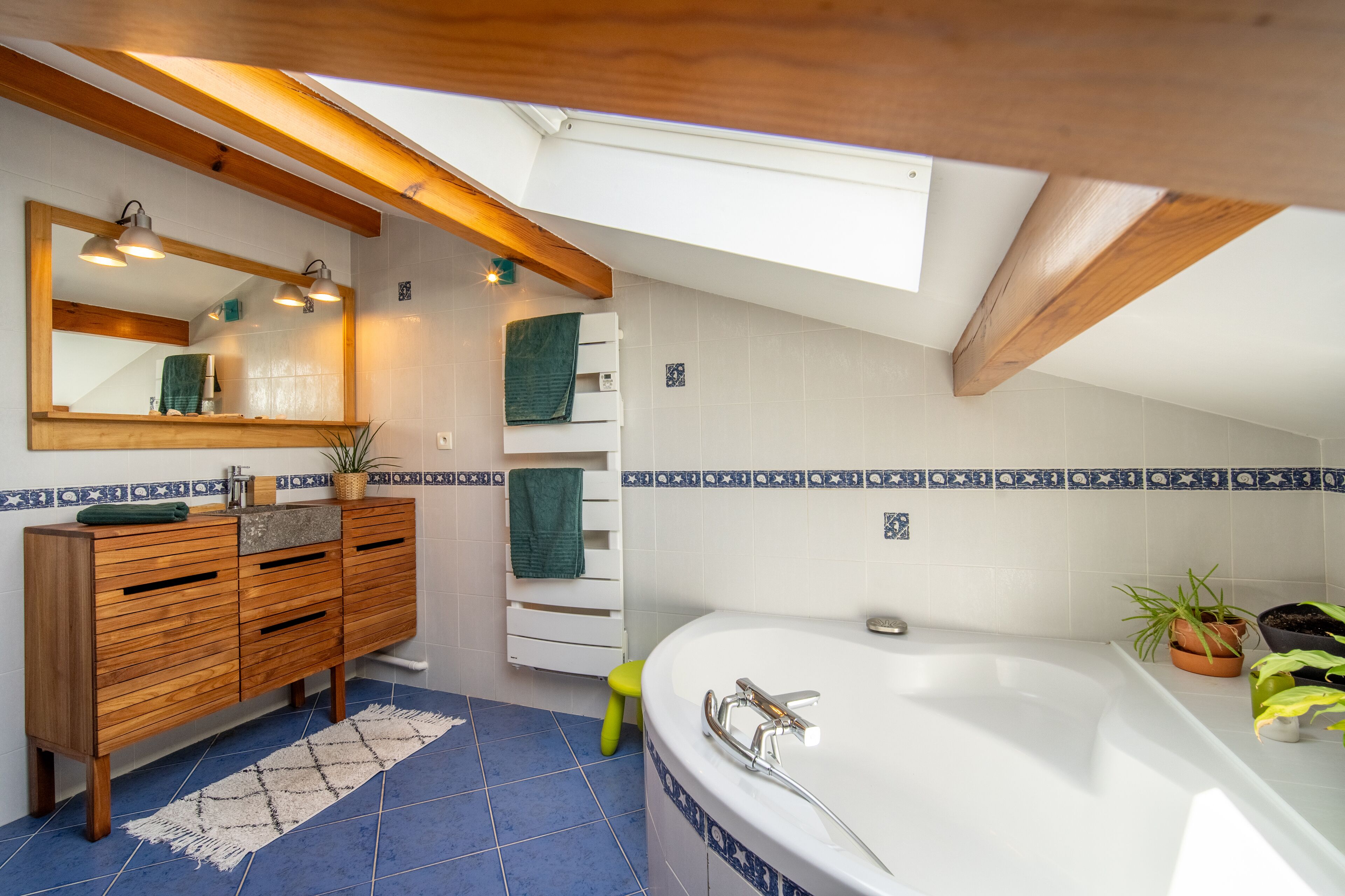 Une salle de bain moderne avec un meuble-lavabo en bois, une baignoire sur pieds et un puits de lumière.