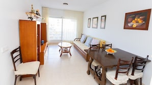 Un comedor con mesa de madera, sillas, un sofá y vista al exterior.