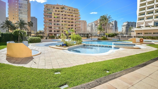 Un complejo residencial con piscina central, rodeado de céspedes cuidados y varios edificios.