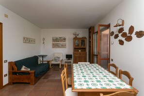 A room with a wooden sofa, a dining table with chairs, a cabinet, and wall decorations. - N212 - Numana, four-room apartment in the center with terrace (Numana)