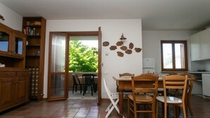 A dining area with a table and chairs, a kitchen with cabinets, and a sliding glass door leading to an outdoor area. - N212 - Numana, four-room apartment in the center with terrace (Numana)