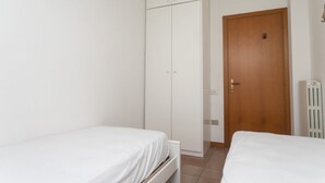 A bedroom with two beds, a wardrobe, a wooden door, and a radiator. - N212 - Numana, four-room apartment in the center with terrace (Numana)