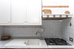 A kitchen with white cabinets, a sink, a stove, and a small stool. - N212 - Numana, four-room apartment in the center with terrace (Numana)