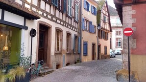 A narrow cobblestone street lined with traditional half-timbered buildings, a bicycle parked by the entrance, and a no-entry sign visible on the right. - "LANDBeautiful beamed apartment in the historic center of Colmar's "Little Venice". (Colmar)