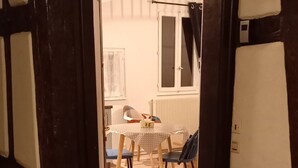 A view from a dark wooden staircase into a room with a table, chairs, and a window. - "LANDBeautiful beamed apartment in the historic center of Colmar's "Little Venice". (Colmar)
