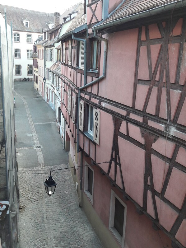 A narrow cobblestone street flanked by traditional half-timbered buildings with exposed wooden beams and shutters. - "LANDBeautiful beamed apartment in the historic center of Colmar's "Little Venice". (Colmar)