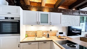 Una cocina moderna con armarios blancos, horno empotrado, microondas, lavabo y encimera de madera.