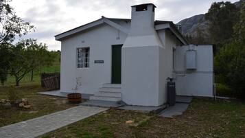 A white building with a green door, steps leading to the entrance, and a chimney.