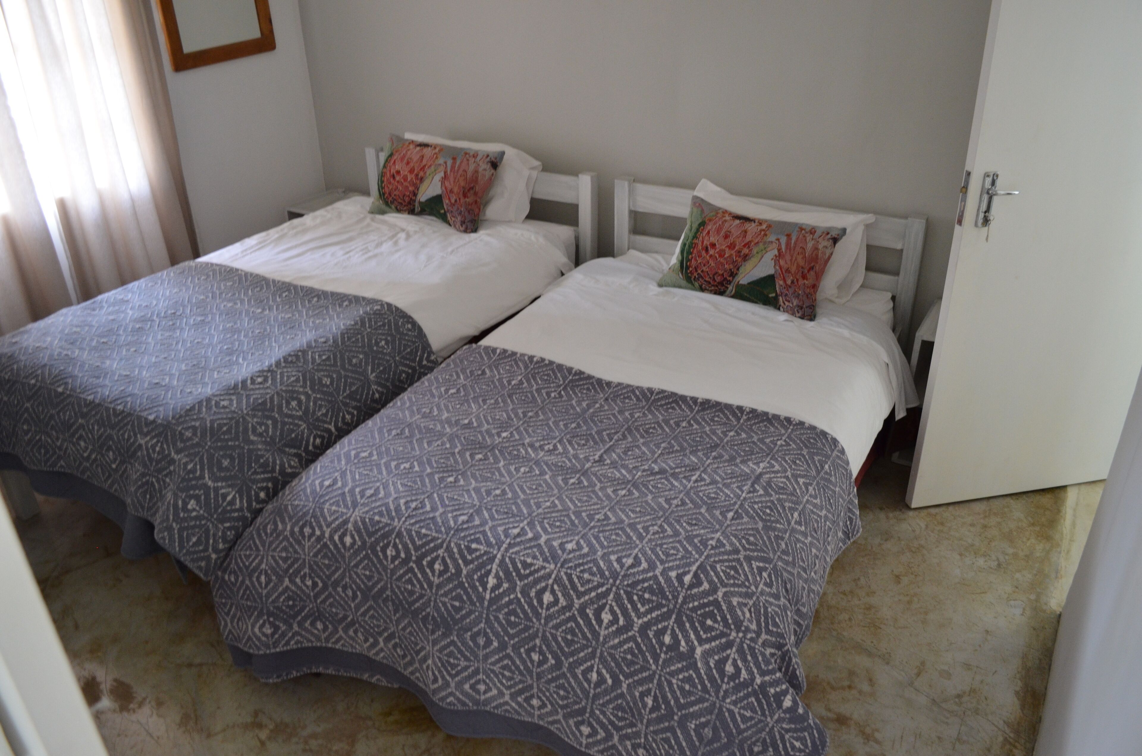 Una habitación de hotel con dos camas, cada una con cubrecamas estampados y almohadones decorativos.