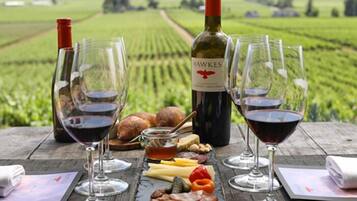 A table set with wine glasses, a bottle of Hawkes wine, and an assortment of cheeses and meats.
