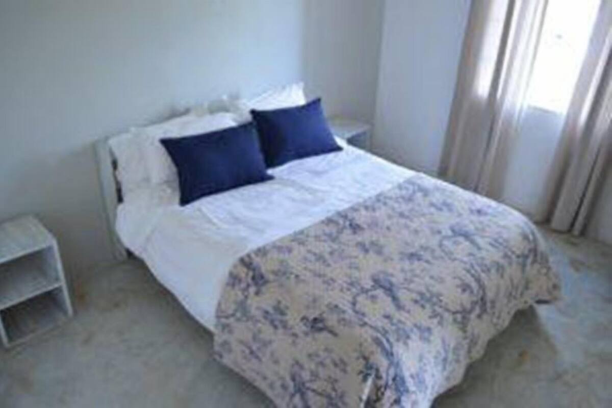 A bedroom with a bed, two pillows, a bedside table, and a nightstand.