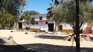 Une cour intérieure avec un bâtiment doté d’un toit en tuiles, d’un garage et d’une entrée fermée par un portail.