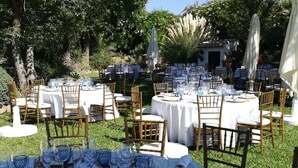 Un espace de restauration en plein air avec des tables rondes recouvertes de nappes blanches, entourées de chaises en bambou.
