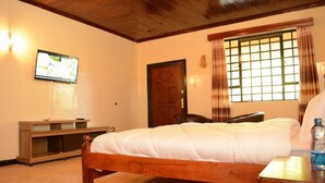 Un dormitorio con cama de madera, televisor en la pared, ventana con cortinas y mesita de noche de madera.