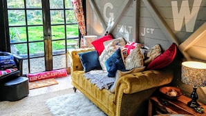 A cozy living room with a yellow sofa, a white furry rug, and a wooden table with a teapot. - Romantic streamside Carriage next to Coast Path ♥️ Short walk to beach & pub! 🥂 (Ruan minor)