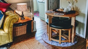 A cozy living room with a yellow sofa, a wooden dining table with chairs, a lamp, and a decorative mirror. - Romantic streamside Carriage next to Coast Path ♥️ Short walk to beach & pub! 🥂 (Ruan minor)