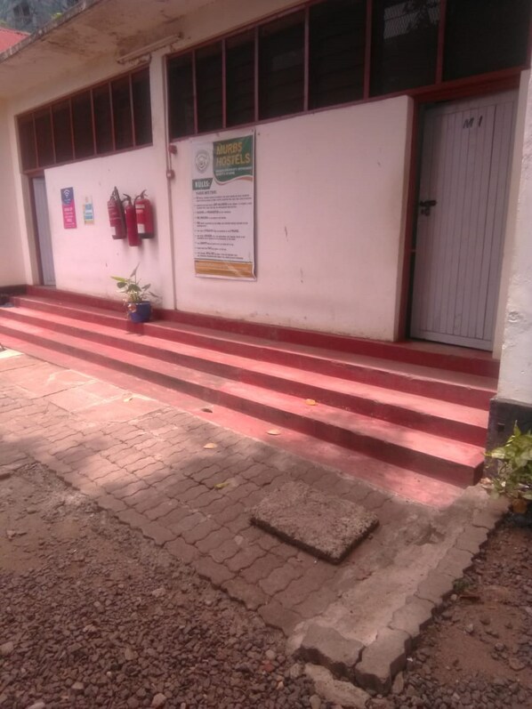 A building with a red and white exterior, a set of red steps leading to a door, and a signboard on the wall.