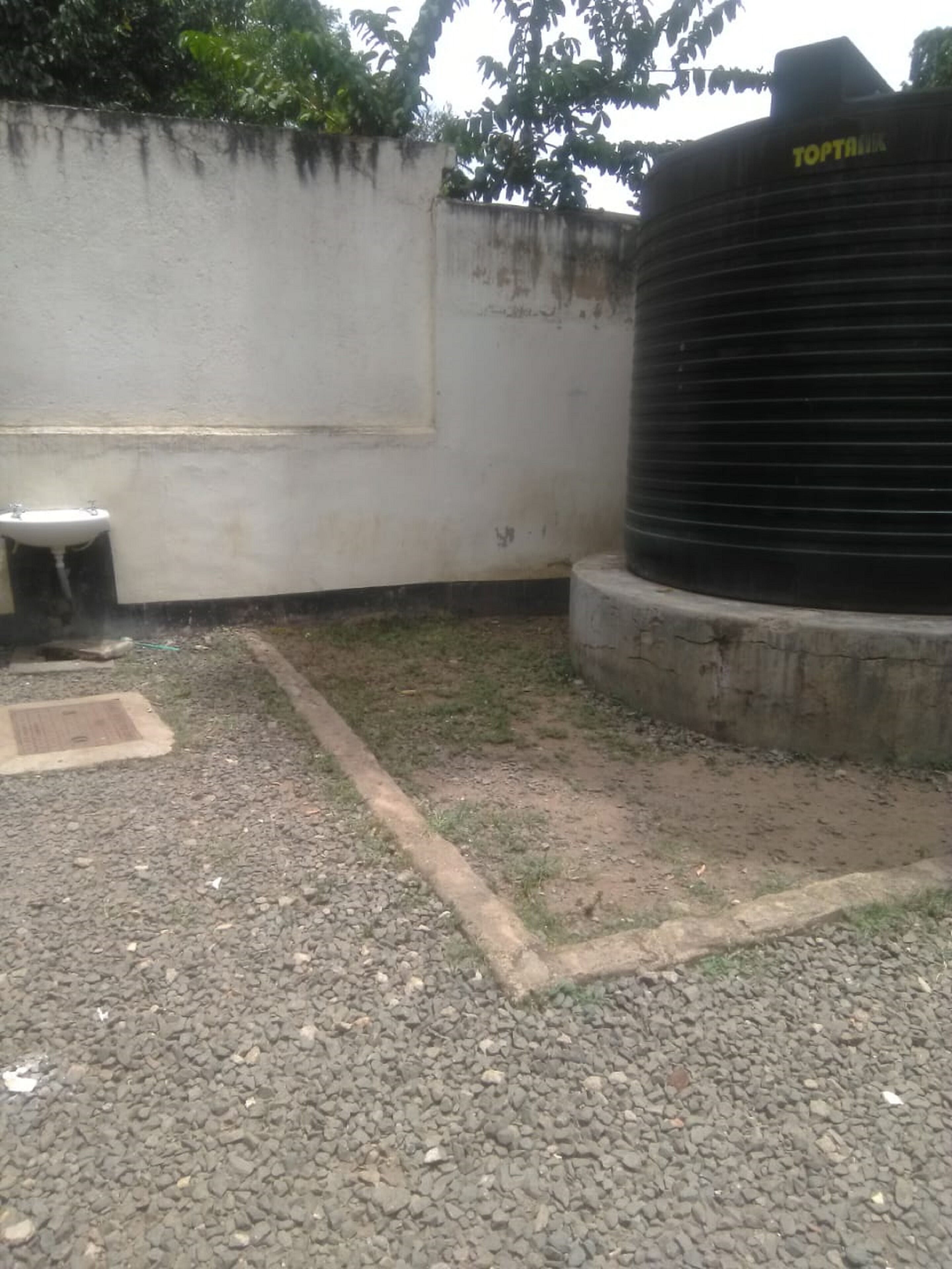 Un réservoir d’eau en béton portant l’inscription « TOPTANK » et un mur blanc avec une fenêtre.