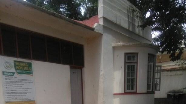 A building with a sign for Murbs Hostels, a set of steps leading to a door, and a paved courtyard. - Murbs Hostel (Kisumu)